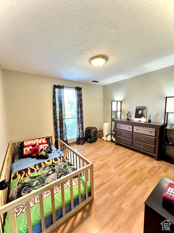 Bedroom featuring a textured ceiling and light hardwood / wood-style flooring