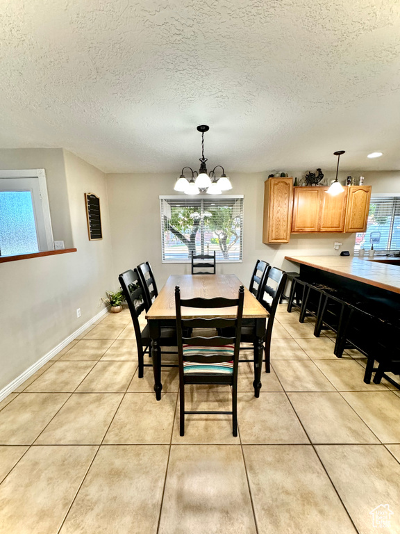 Tiled dining area with a notable chandelier and a textured ceiling