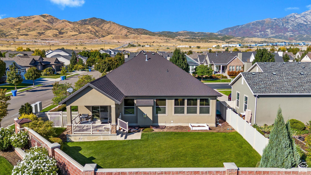 Back of house with a mountain view and a yard