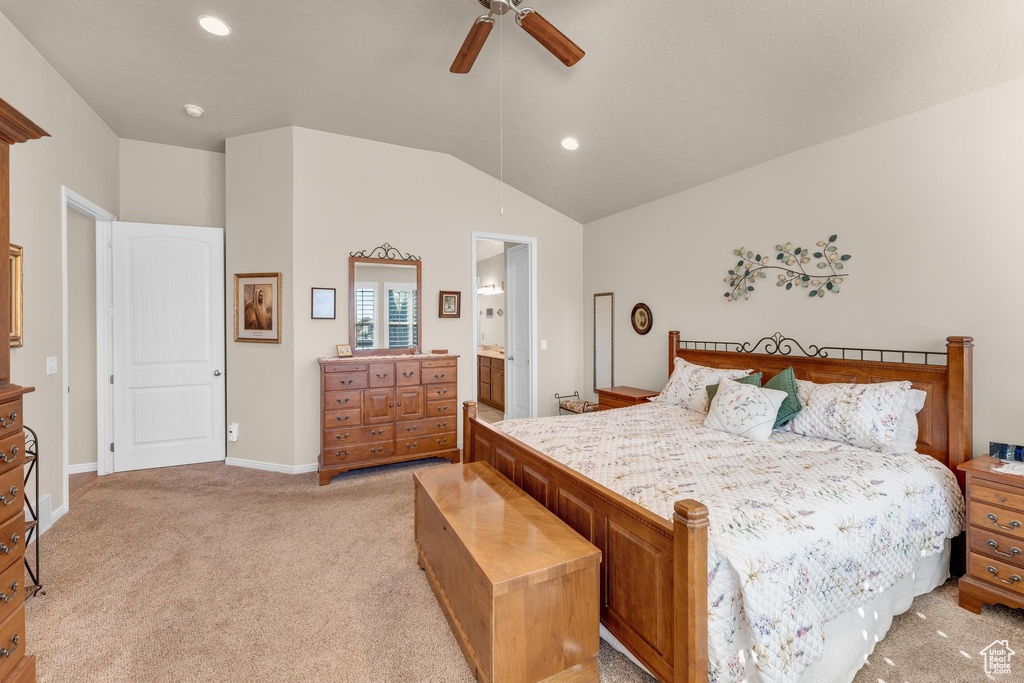 Bedroom featuring light carpet, vaulted ceiling, ceiling fan, and ensuite bathroom