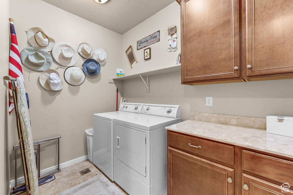 Laundry room featuring a textured ceiling, separate washer and dryer, and cabinets