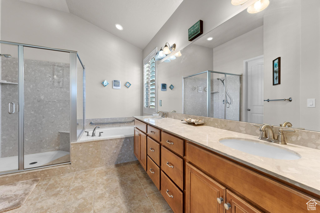 Bathroom featuring shower with separate bathtub, vaulted ceiling, vanity, and tile patterned floors