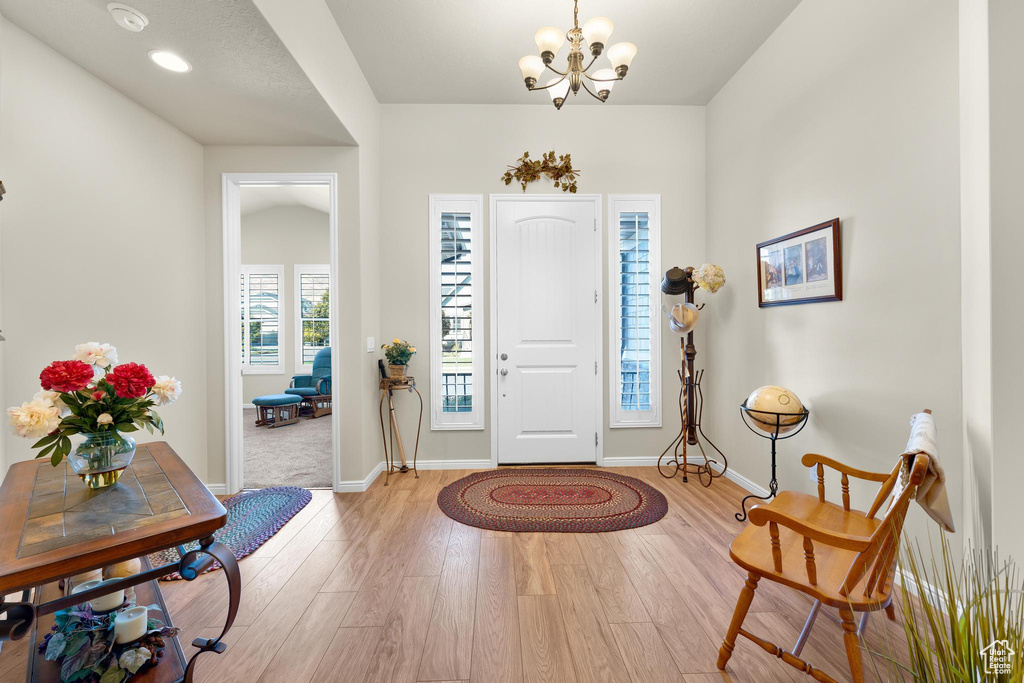 Foyer with light wood-type flooring and a chandelier