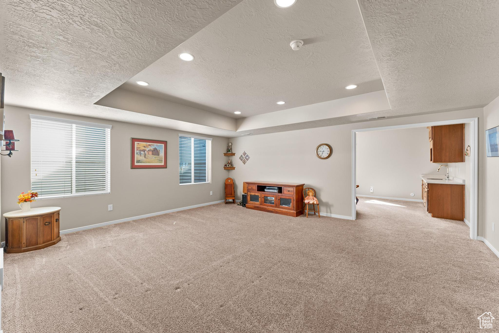 Game room with a textured ceiling, a tray ceiling, and light colored carpet