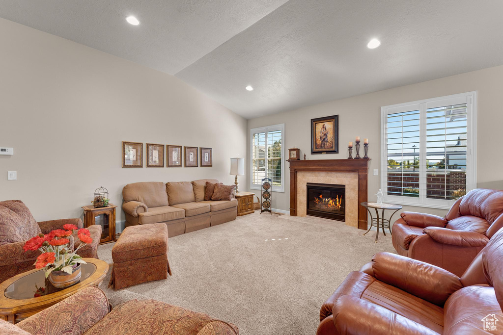 Carpeted living room featuring a tiled fireplace and vaulted ceiling