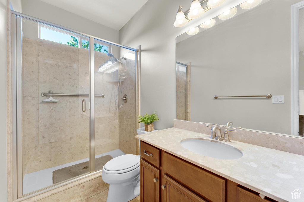 Bathroom with tile patterned flooring, vanity, toilet, and a shower with door