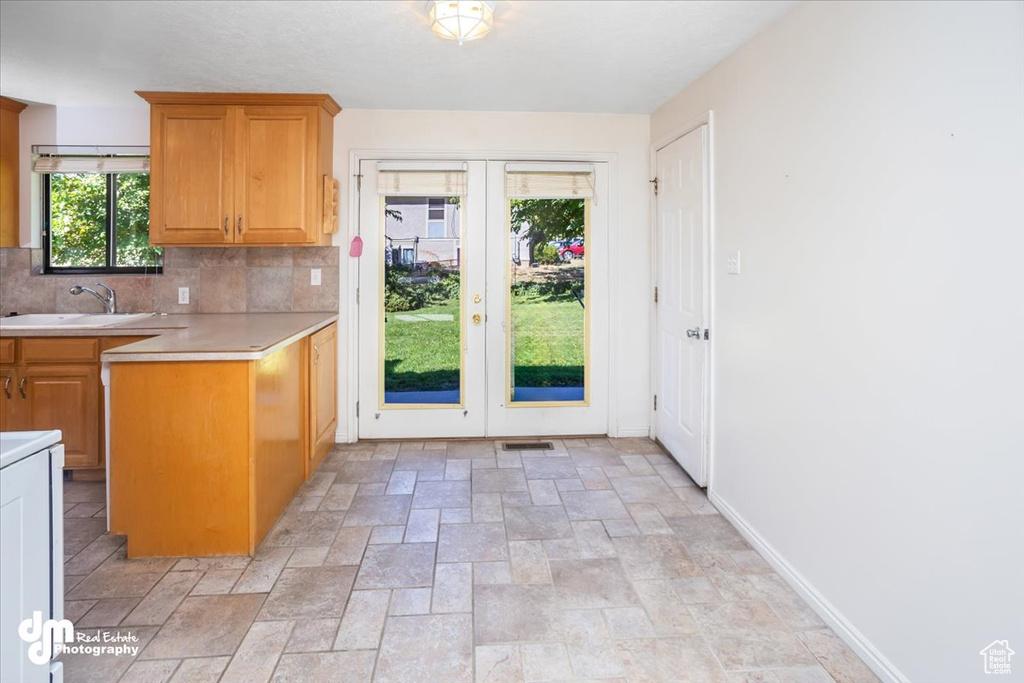 Kitchen featuring decorative backsplash, french doors, and sink