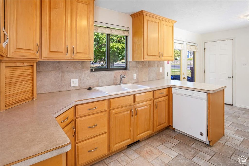 Kitchen featuring a healthy amount of sunlight, kitchen peninsula, dishwasher, and sink