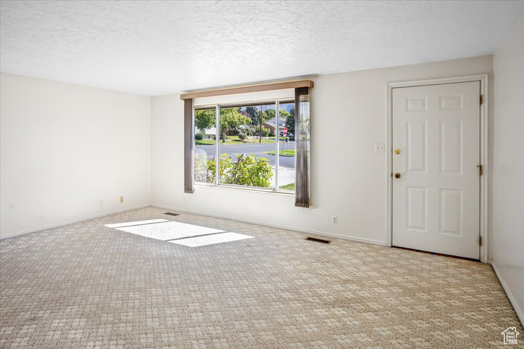 Carpeted empty room with a textured ceiling