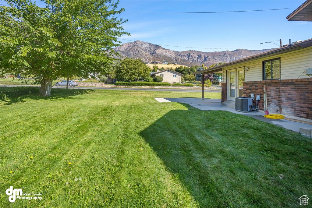 View of yard featuring cooling unit, a mountain view, and a patio