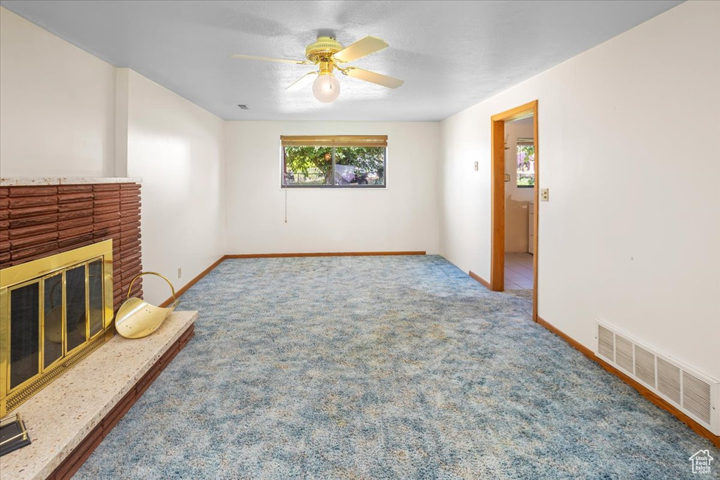 Living room with carpet, ceiling fan, and a brick fireplace