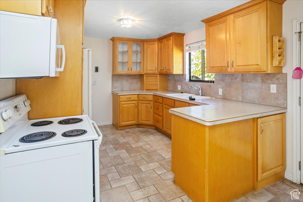 Kitchen with backsplash, white appliances, sink, and kitchen peninsula