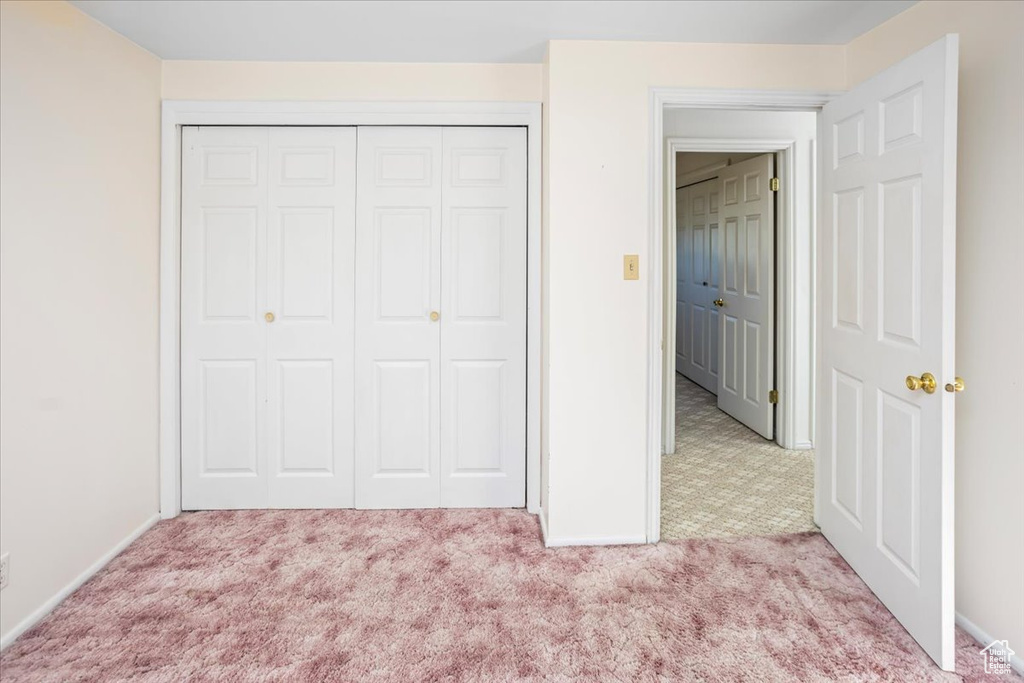 Unfurnished bedroom with light carpet and a closet