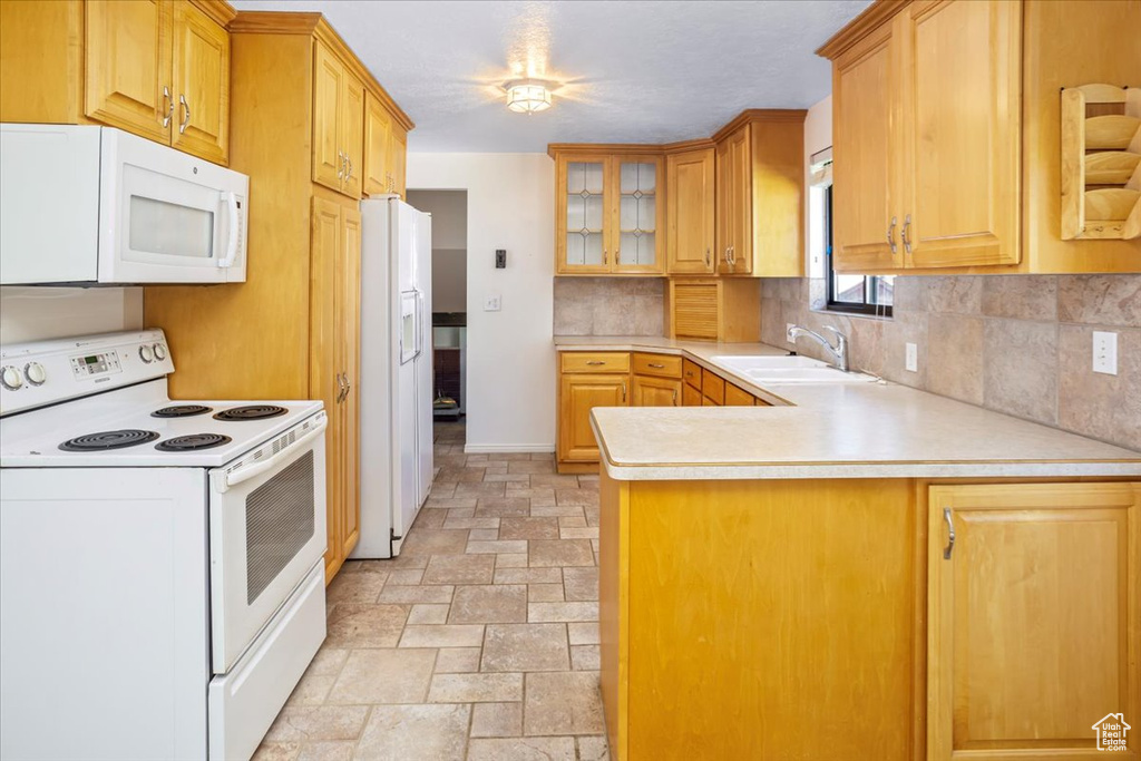 Kitchen with backsplash, white appliances, sink, and kitchen peninsula