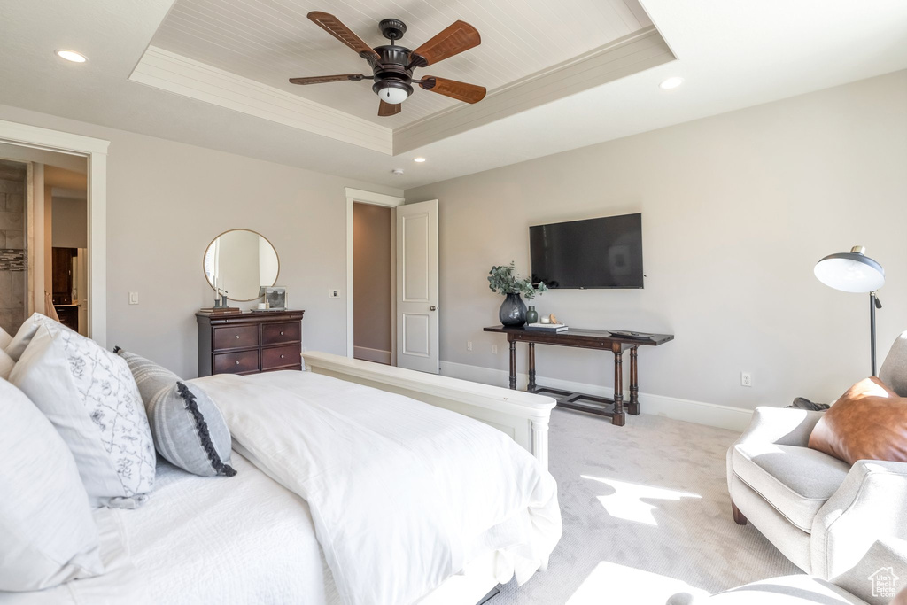 Bedroom with a raised ceiling, light carpet, and ceiling fan