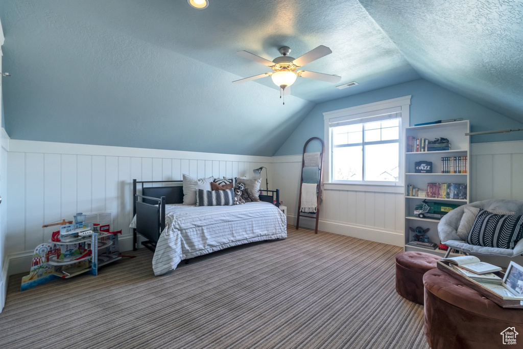 Carpeted bedroom featuring vaulted ceiling, ceiling fan, and a textured ceiling