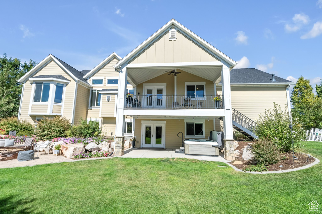 Back of property with ceiling fan, a patio, french doors, a yard, and a balcony