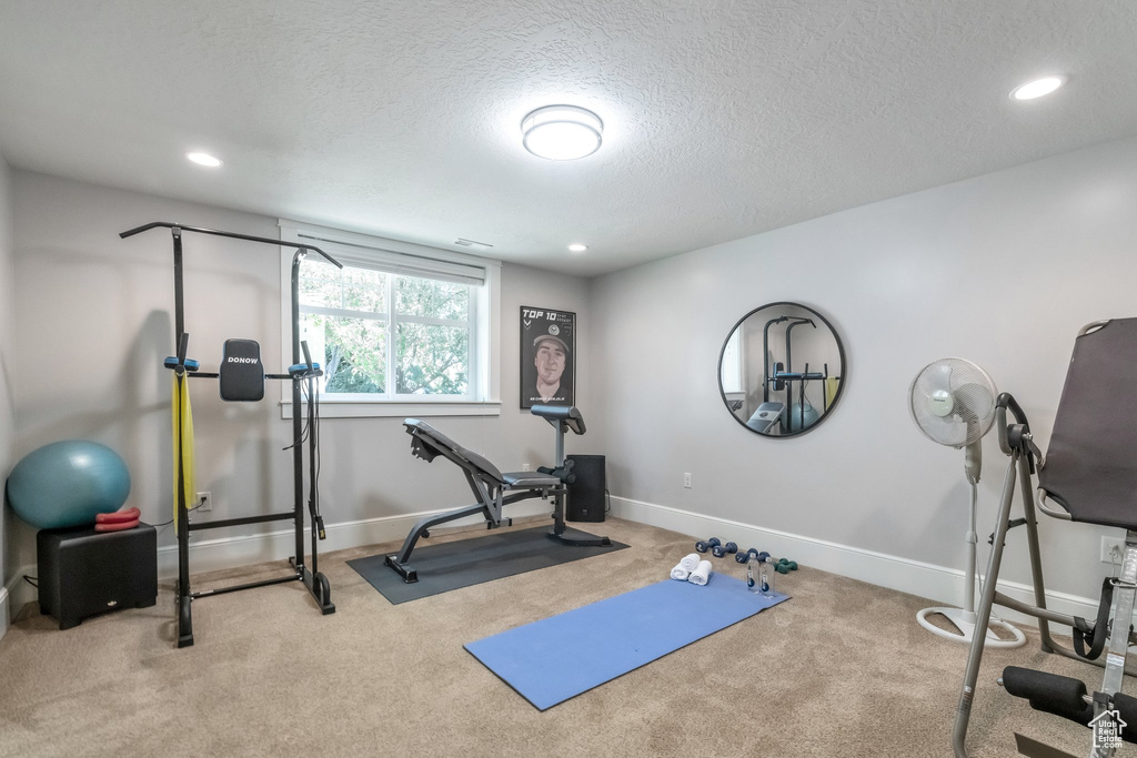 Exercise area with light carpet and a textured ceiling