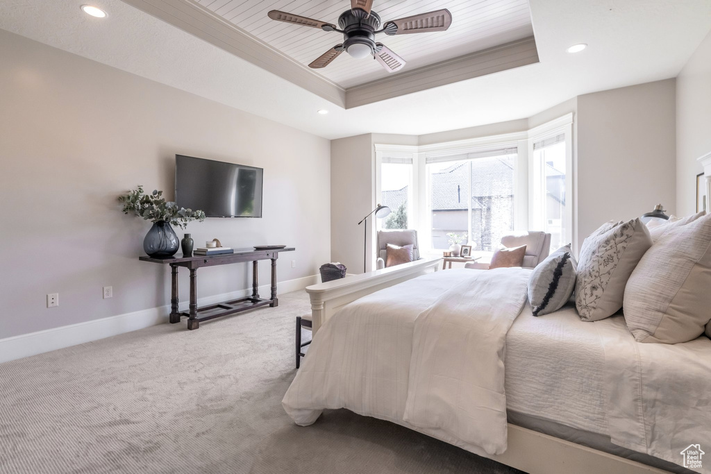 Carpeted bedroom with ceiling fan and a tray ceiling