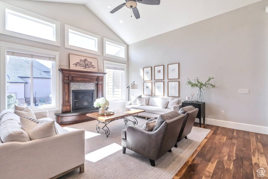 Living room featuring a tiled fireplace, ceiling fan, dark hardwood / wood-style floors, and plenty of natural light