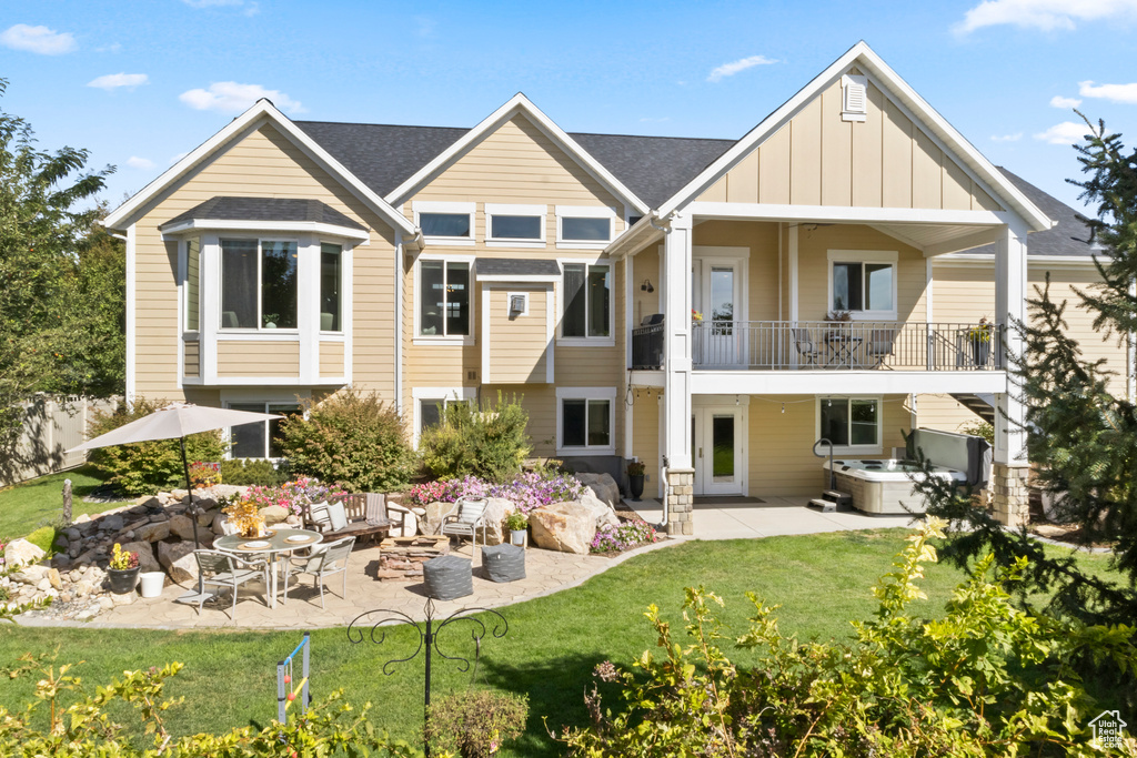 Rear view of property with a yard, a hot tub, a balcony, and a patio area