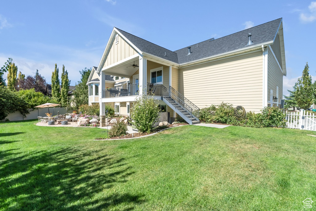 Back of property with ceiling fan, a patio area, and a yard