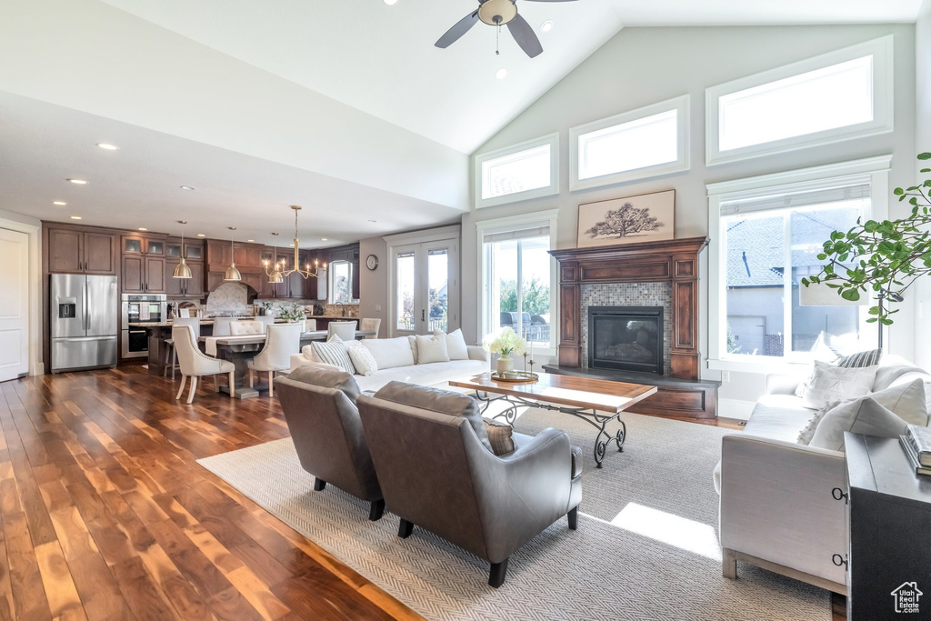 Living room featuring ceiling fan with notable chandelier, high vaulted ceiling, and dark wood-type flooring