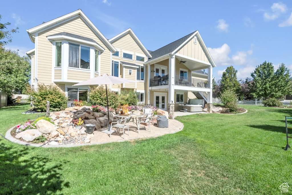 Back of house featuring a balcony, ceiling fan, a patio area, and a yard