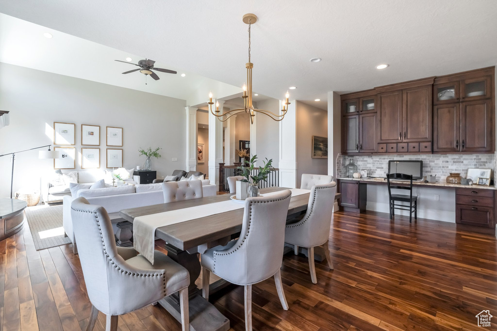 Dining room with ceiling fan with notable chandelier and dark wood-type flooring