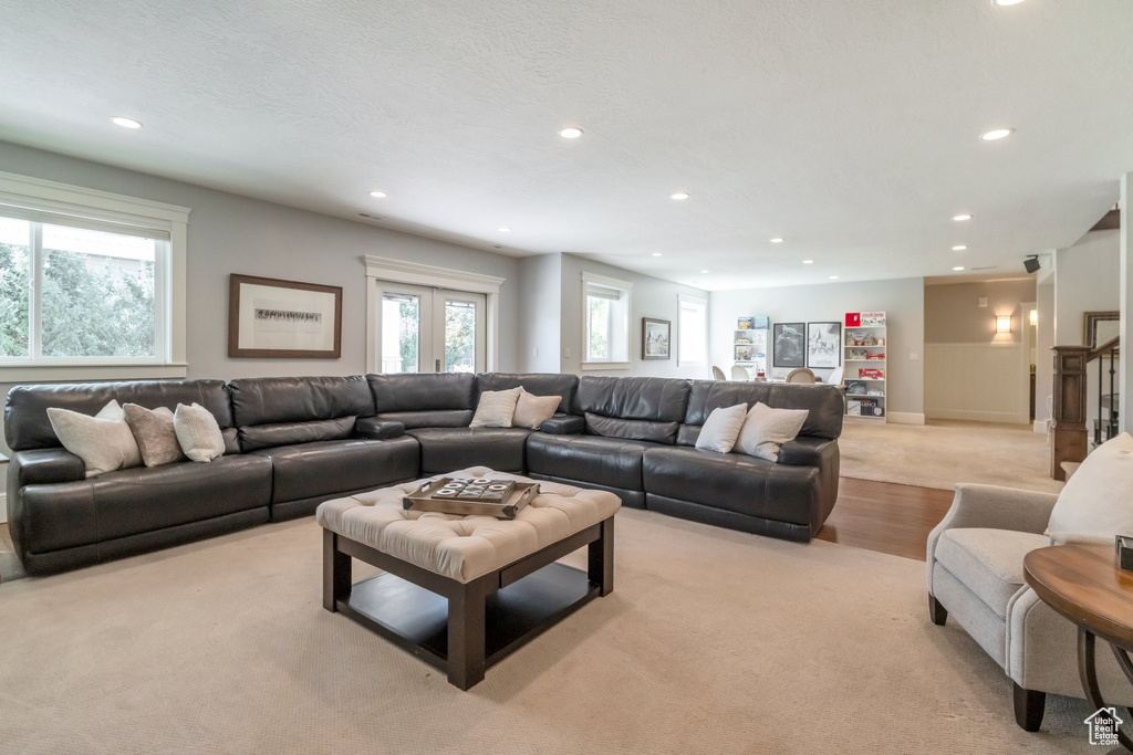 Carpeted living room with a textured ceiling, french doors, and plenty of natural light