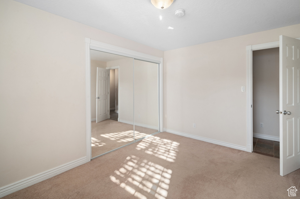 Unfurnished bedroom with light colored carpet and a closet