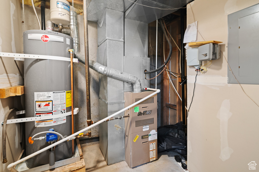 Utility room featuring electric panel and secured water heater