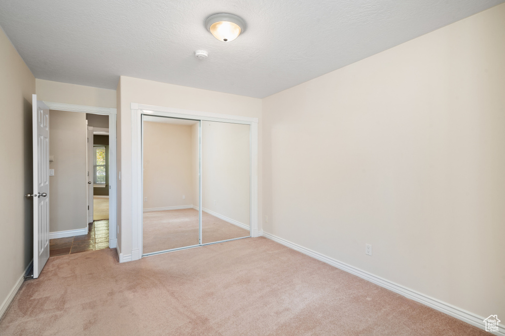 Unfurnished bedroom featuring light colored carpet and a closet