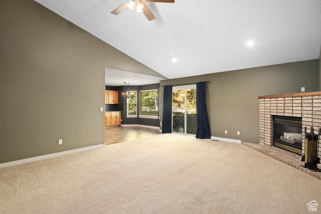 Unfurnished living room featuring high vaulted ceiling, ceiling fan, light colored carpet, and a fireplace