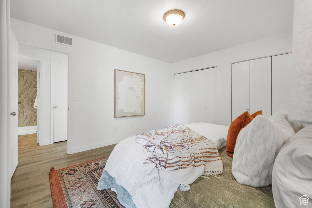 Bedroom with wood-type flooring and two closets