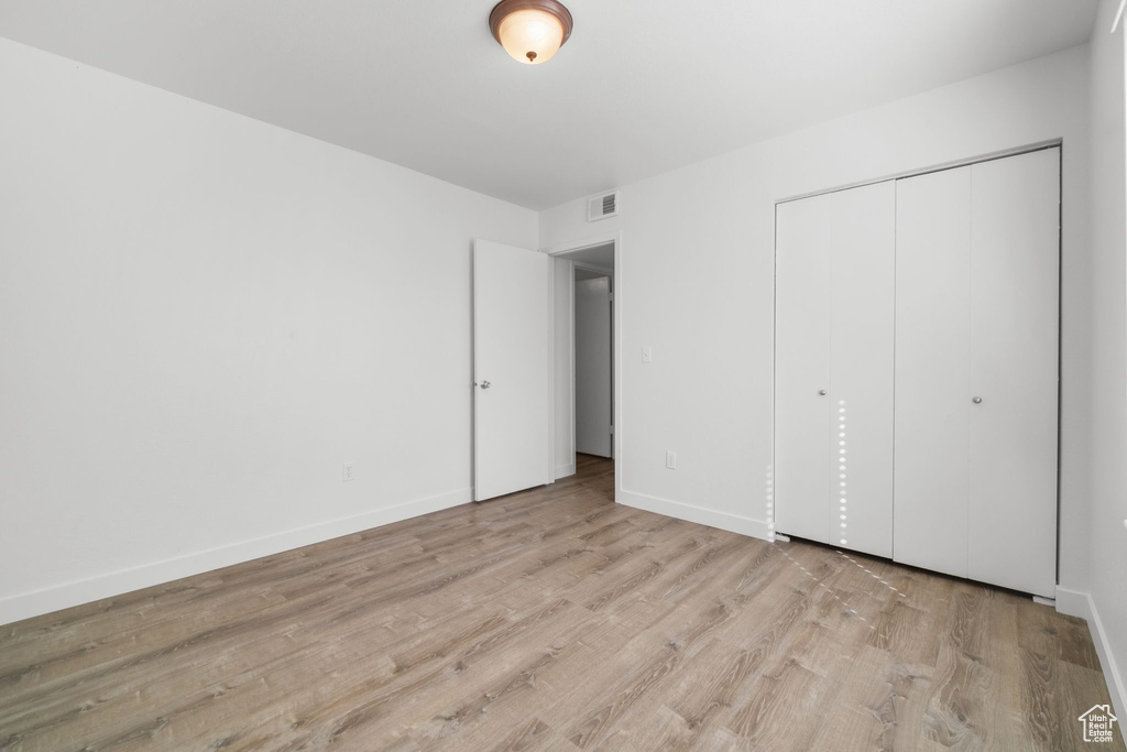 Unfurnished bedroom with light wood-type flooring and a closet