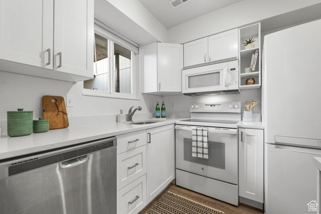 Kitchen with white appliances, white cabinetry, sink, and dark wood-type flooring