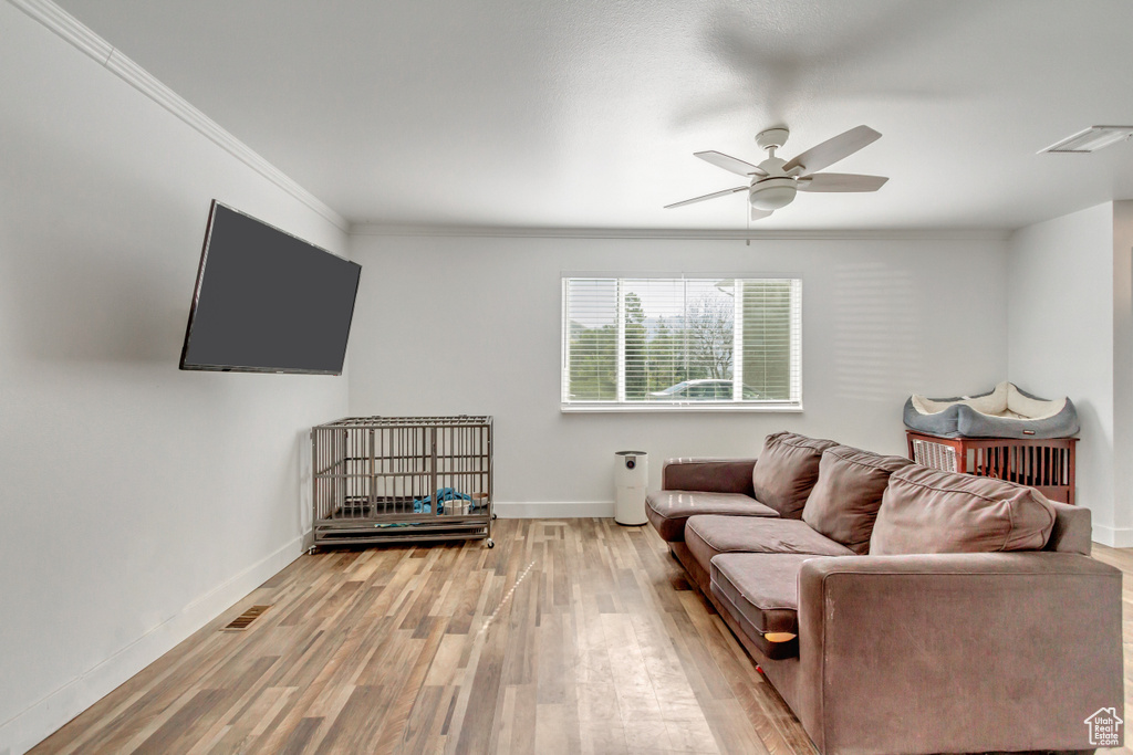 Living room featuring ceiling fan, hardwood / wood-style flooring, and crown molding