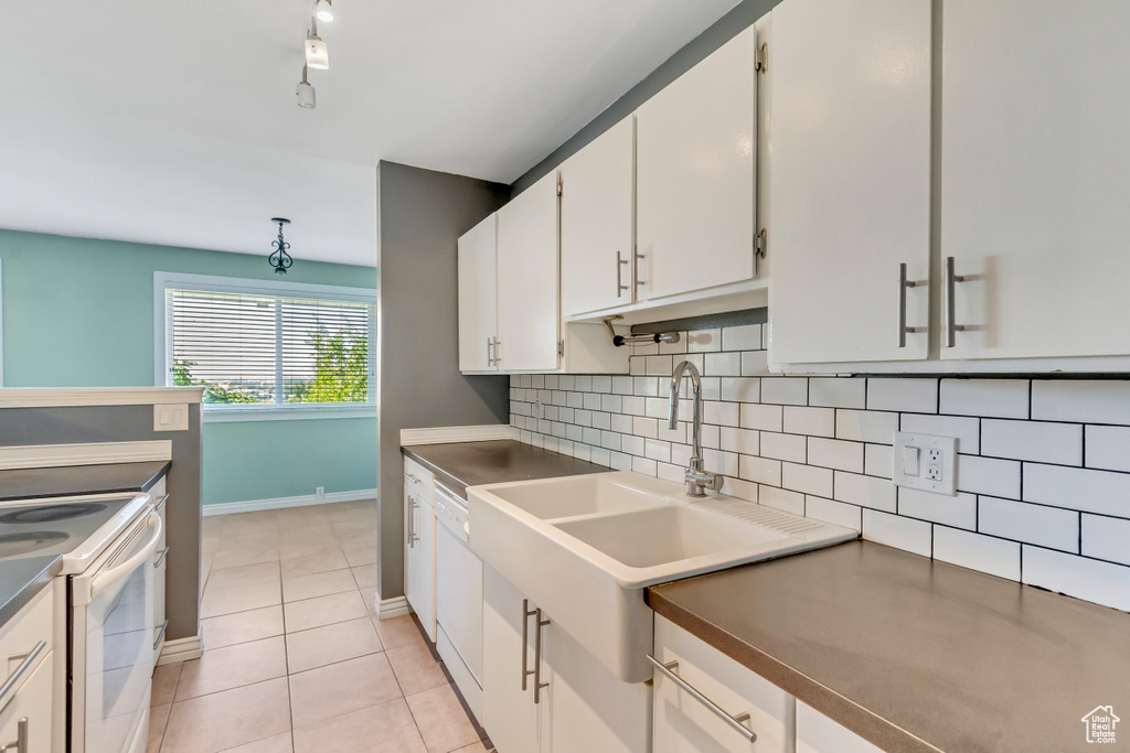 Kitchen featuring white appliances, white cabinetry, light tile patterned floors, and tasteful backsplash