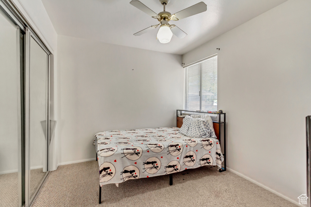 Carpeted bedroom with a closet and ceiling fan