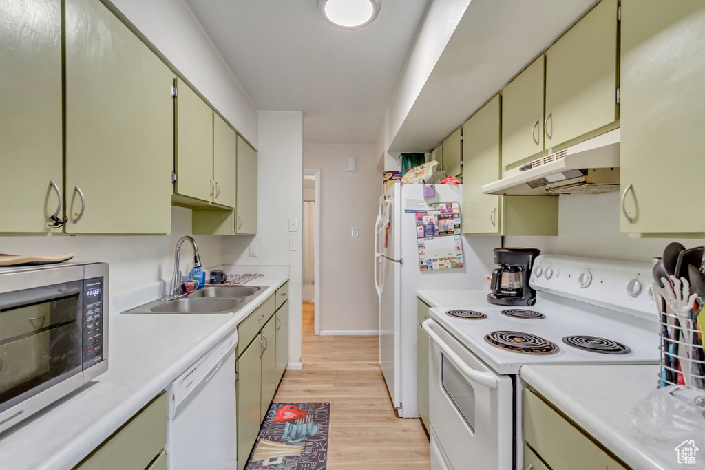 Kitchen featuring light wood-type flooring, white appliances, green cabinetry, and sink