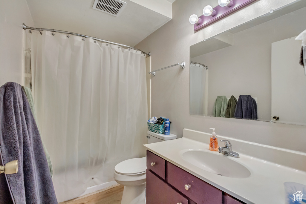 Bathroom with a shower with shower curtain, wood-type flooring, vanity, and toilet