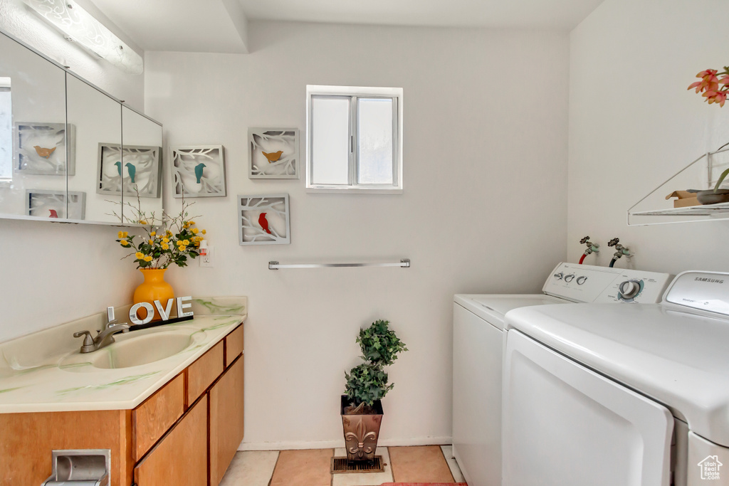 Laundry room featuring light tile patterned floors, cabinets, sink, and washing machine and clothes dryer