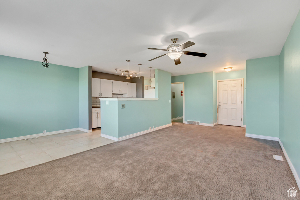 Unfurnished living room featuring rail lighting, ceiling fan, and light colored carpet