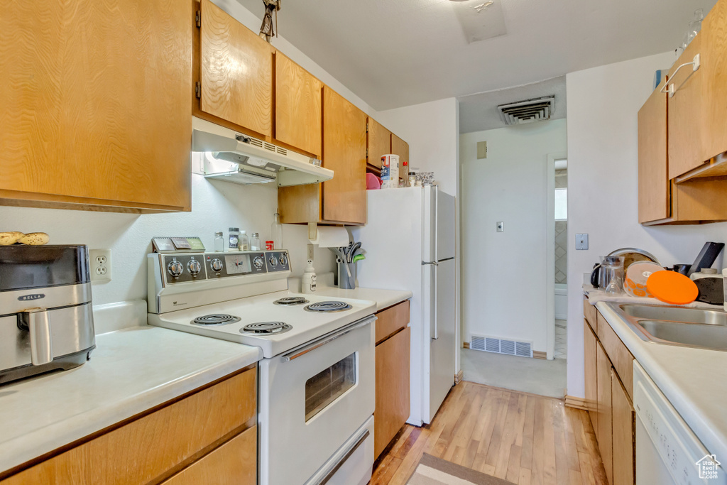 Kitchen featuring light wood-type flooring, white appliances, and sink