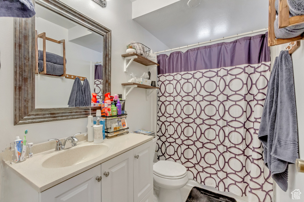 Bathroom featuring curtained shower, vanity, and toilet