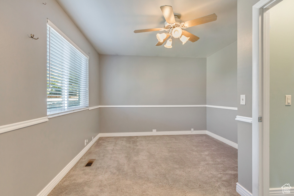 Carpeted empty room featuring ceiling fan