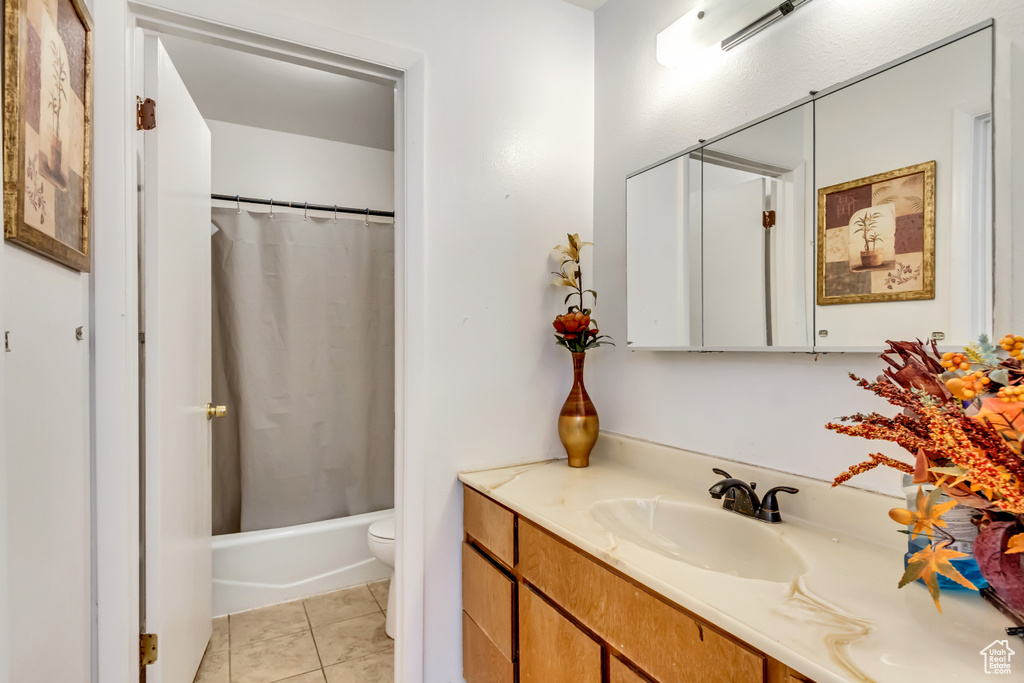 Full bathroom featuring shower / bath combo, tile patterned flooring, vanity, and toilet