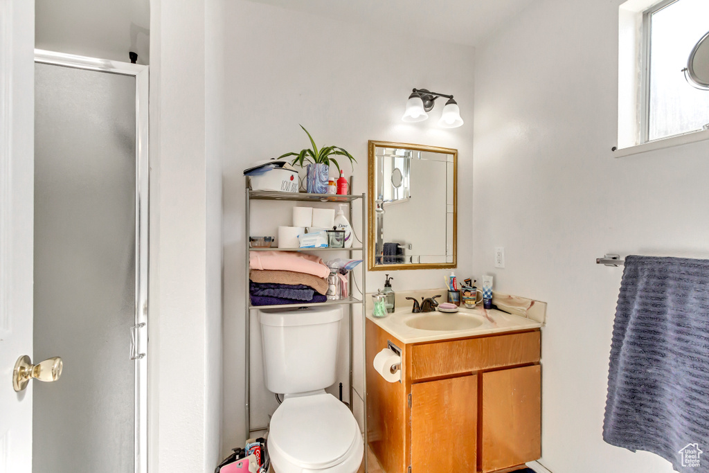 Bathroom featuring walk in shower, vanity, and toilet