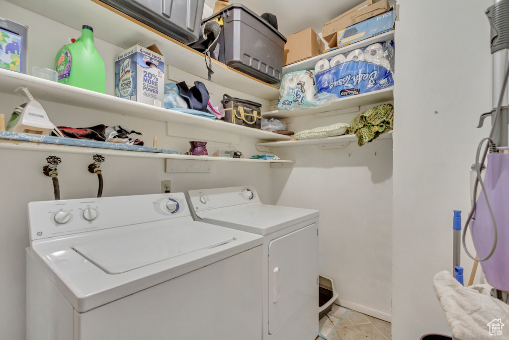 Clothes washing area featuring light tile patterned flooring and washing machine and dryer